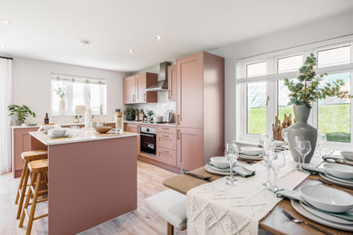 Inspiration for a medium sized contemporary l-shaped kitchen/diner in Dorset with an integrated sink, shaker cabinets, pink cabinets, white splashback, light hardwood flooring, an island, beige floors and white worktops.