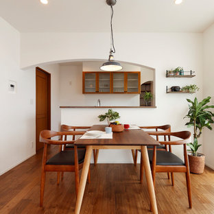 Offenes Asiatisches Esszimmer mit weißer Wandfarbe, braunem Holzboden und braunem Boden in Sonstige