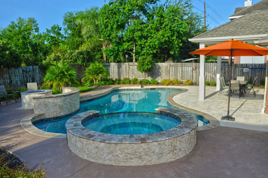 Design ideas for a large contemporary backyard custom-shaped natural pool in Houston with a water feature and natural stone pavers.