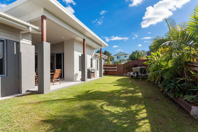 Mid-sized contemporary backyard patio in Sunshine Coast with natural stone pavers and a roof extension.