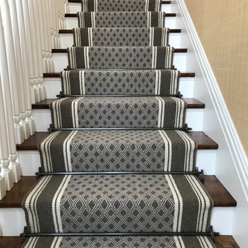 Custom stair runner with applied border and decorative stair rods