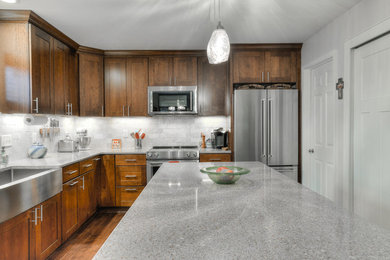 Mid-sized transitional l-shaped separate kitchen in Detroit with a farmhouse sink, shaker cabinets, dark wood cabinets, granite benchtops, grey splashback, stone tile splashback, stainless steel appliances, dark hardwood floors and with island.