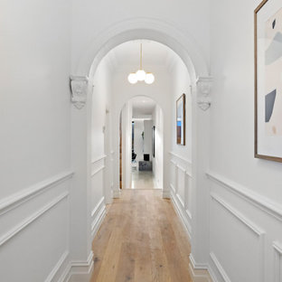 Idéer för en mellanstor modern hall, med vita väggar och ljust trägolv