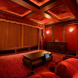 Exemple d'une salle de cinéma chic fermée avec un mur rouge, un écran de projection et un sol rouge.