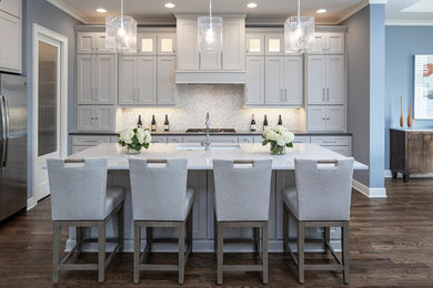 Inspiration for a large transitional galley eat-in kitchen in Kansas City with an undermount sink, white cabinets, quartzite benchtops, white splashback, mosaic tile splashback, stainless steel appliances, medium hardwood floors, with island, brown floor, white benchtop and shaker cabinets.
