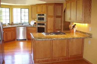 Kitchen - mid-sized traditional u-shaped medium tone wood floor kitchen idea in San Francisco with a double-bowl sink, shaker cabinets, light wood cabinets, granite countertops and stainless steel appliances