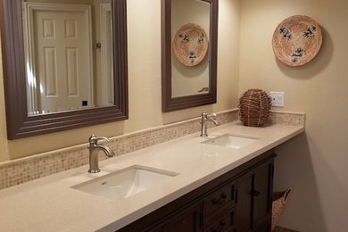 Inspiration for a mid-sized traditional 3/4 bathroom in Phoenix with recessed-panel cabinets, dark wood cabinets, a corner shower, beige walls, medium hardwood floors, an undermount sink, engineered quartz benchtops, brown floor, a hinged shower door and beige benchtops.