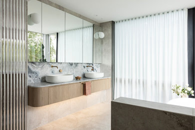 Photo of a large contemporary bathroom in Sydney with flat-panel cabinets, medium wood cabinets, a freestanding tub, an open shower, a wall-mount toilet, beige tile, porcelain tile, beige walls, porcelain floors, a vessel sink, quartzite benchtops, beige floor, an open shower, blue benchtops, a niche and a double vanity.