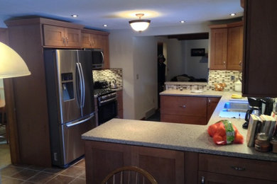 Small elegant l-shaped brown floor and ceramic tile enclosed kitchen photo in New York with a double-bowl sink, shaker cabinets, white cabinets, granite countertops, beige backsplash, stainless steel appliances and no island