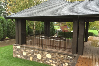 This is an example of a large contemporary backyard patio in Vancouver with decking, a fire feature and a roof extension.