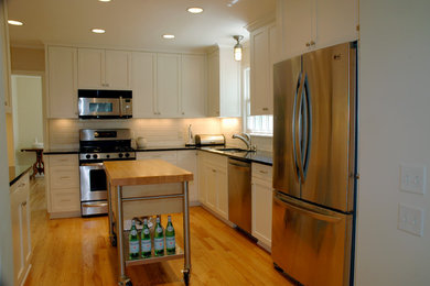 Open concept kitchen - traditional l-shaped light wood floor open concept kitchen idea in Minneapolis with shaker cabinets, white cabinets, granite countertops, white backsplash, subway tile backsplash, stainless steel appliances and an island