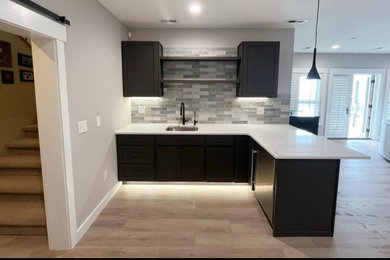 Example of a mid-sized minimalist l-shaped laminate floor home bar design in Boise with an undermount sink, shaker cabinets, dark wood cabinets, quartzite countertops, gray backsplash, ceramic backsplash and white countertops