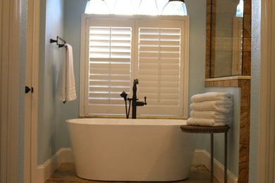 Transitional porcelain tile and brown floor freestanding bathtub photo in Tampa with blue walls