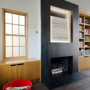 Photo of a large modern home office and library in Sacramento with a reading nook, white walls, dark hardwood flooring, a standard fireplace, a concrete fireplace surround and black floors.