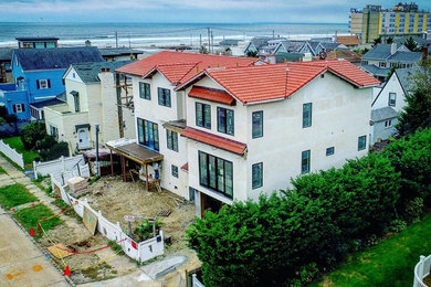 Example of a huge tuscan multicolored three-story stucco house exterior design in New York with a gambrel roof and a tile roof