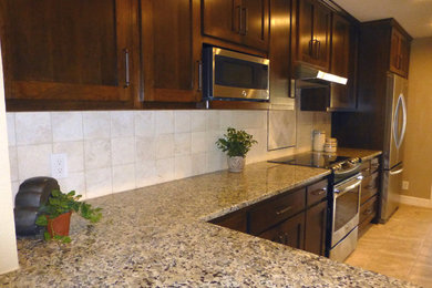 Example of a huge classic u-shaped travertine floor eat-in kitchen design in Austin with an undermount sink, shaker cabinets, dark wood cabinets, granite countertops, beige backsplash, stone tile backsplash, stainless steel appliances and an island