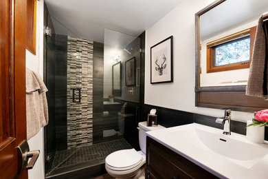 Alcove shower - small transitional 3/4 gray tile and porcelain tile brown floor and single-sink alcove shower idea in Other with dark wood cabinets, a two-piece toilet, white walls, an integrated sink, solid surface countertops, a hinged shower door, white countertops and a freestanding vanity