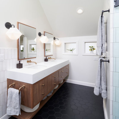 Example of a mid-sized transitional master white tile and ceramic tile porcelain tile, black floor, double-sink and vaulted ceiling bathroom design in Portland with flat-panel cabinets, brown cabinets, a wall-mount toilet, white walls, an undermount sink, quartz countertops, a hinged shower door, white countertops and a floating vanity
