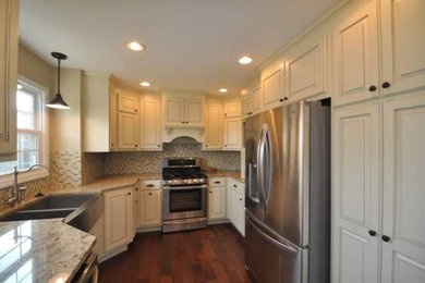 Inspiration for a mid-sized timeless u-shaped dark wood floor enclosed kitchen remodel in Kansas City with a farmhouse sink, raised-panel cabinets, white cabinets, granite countertops, gray backsplash, mosaic tile backsplash, stainless steel appliances and no island