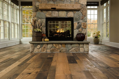 Example of a light wood floor and brown floor family room design in Chicago with beige walls, a standard fireplace, a stone fireplace and no tv