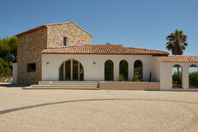 Aménagement d'une grande façade de maison beige en pierre à un étage avec un toit à deux pans, un toit en tuile et un toit rouge.