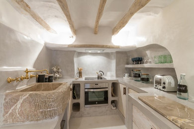 Inspiration for a small mediterranean u-shaped separate kitchen in Edinburgh with flat-panel cabinets, distressed cabinets, concrete benchtops, stainless steel appliances, white floor, grey benchtop, grey splashback and a farmhouse sink.