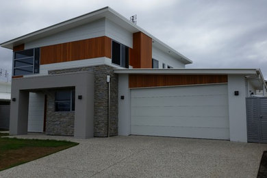 Photo of a large modern two-storey white exterior in Gold Coast - Tweed with mixed siding and a flat roof.