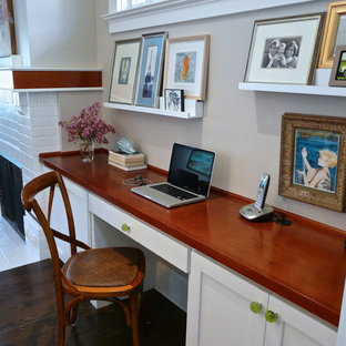 Klassisk inredning av ett litet hemmabibliotek, med grå väggar, mörkt trägolv, en standard öppen spis, en spiselkrans i tegelsten och ett inbyggt skrivbord