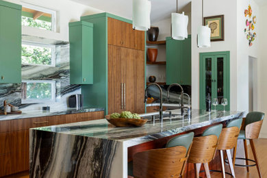 Open concept kitchen - large modern galley bamboo floor, beige floor and vaulted ceiling open concept kitchen idea in Other with a drop-in sink, flat-panel cabinets, green cabinets, quartzite countertops, green backsplash, stone slab backsplash, paneled appliances, an island and green countertops