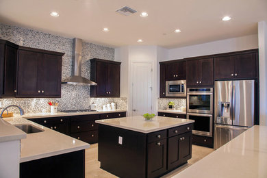 Inspiration for a huge contemporary u-shaped light wood floor eat-in kitchen remodel in Phoenix with a drop-in sink, recessed-panel cabinets, dark wood cabinets, granite countertops, multicolored backsplash, glass tile backsplash, stainless steel appliances and two islands