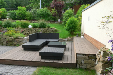 Inspiration for a mid-sized contemporary sloped garden in Dortmund with a retaining wall and decking.