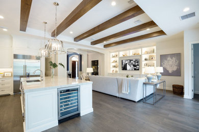 Open concept kitchen - large transitional single-wall medium tone wood floor, brown floor and exposed beam open concept kitchen idea in Orlando with an undermount sink, flat-panel cabinets, white cabinets, quartz countertops, gray backsplash, quartz backsplash, stainless steel appliances, an island and gray countertops
