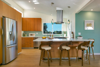Example of a mid-sized 1960s l-shaped light wood floor and beige floor open concept kitchen design in San Diego with a double-bowl sink, flat-panel cabinets, light wood cabinets, quartz countertops, green backsplash, glass tile backsplash, stainless steel appliances, an island and white countertops