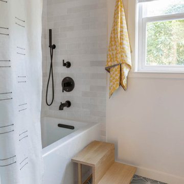 Shower-Tub with Modern Black Plumbing, Wooden Step Stool, and Colorful Accents