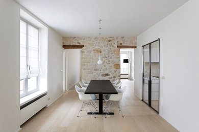 This is an example of a large contemporary separate dining room in Paris with white walls, light hardwood floors and no fireplace.