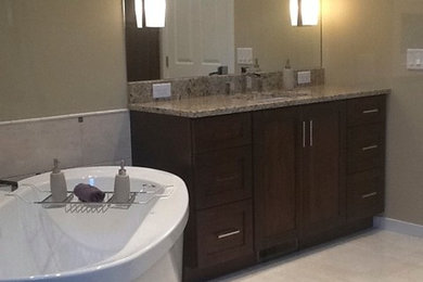 Inspiration for a mid-sized traditional master bathroom in Grand Rapids with an undermount sink, recessed-panel cabinets, medium wood cabinets, granite benchtops, a freestanding tub, an open shower, a two-piece toilet, beige tile, ceramic tile, beige walls and ceramic floors.
