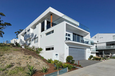 This is an example of an expansive contemporary two-storey white exterior in Newcastle - Maitland with concrete fiberboard siding and a flat roof.