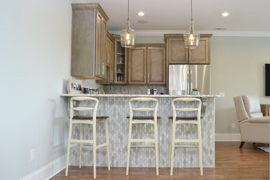 Example of a small transitional u-shaped brown floor and medium tone wood floor open concept kitchen design in Other with a single-bowl sink, raised-panel cabinets, granite countertops, stainless steel appliances, no island, light wood cabinets, metallic backsplash and glass sheet backsplash