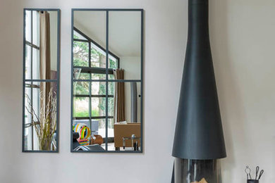 Idée de décoration pour un grand salon design ouvert avec un mur beige, parquet clair, un poêle à bois, un manteau de cheminée en métal et un sol beige.