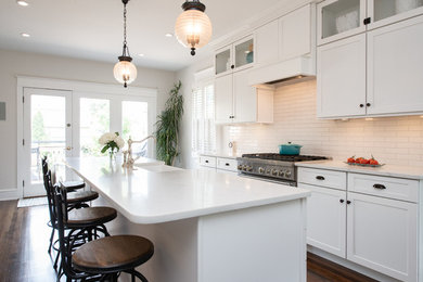 Large transitional galley dark wood floor and brown floor eat-in kitchen photo in Philadelphia with a farmhouse sink, shaker cabinets, white cabinets, marble countertops, white backsplash, subway tile backsplash, paneled appliances, an island and white countertops