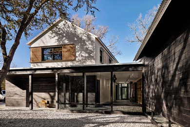 Photo of a modern two-storey black house exterior in Austin with mixed siding, a metal roof and a shed roof.