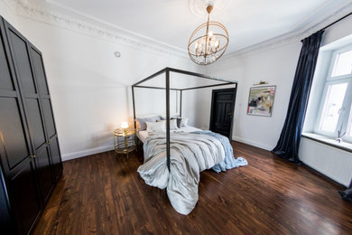 Modelo de dormitorio principal clásico grande con paredes blancas y suelo de madera oscura