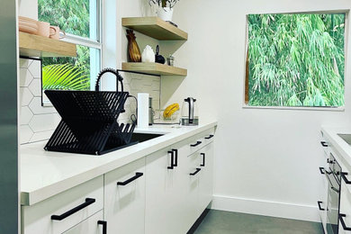 Inspiration for a small modern galley porcelain tile and gray floor kitchen remodel in Miami with a single-bowl sink, flat-panel cabinets, white cabinets, quartz countertops, white backsplash, porcelain backsplash, stainless steel appliances and white countertops