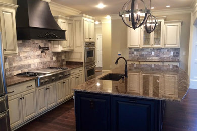Inspiration for a large contemporary l-shaped medium tone wood floor eat-in kitchen remodel in Other with an undermount sink, raised-panel cabinets, beige cabinets, marble countertops, beige backsplash, stone tile backsplash, stainless steel appliances and an island