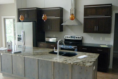 Example of an eclectic single-wall light wood floor eat-in kitchen design in Other with an undermount sink, flat-panel cabinets, dark wood cabinets, granite countertops and an island