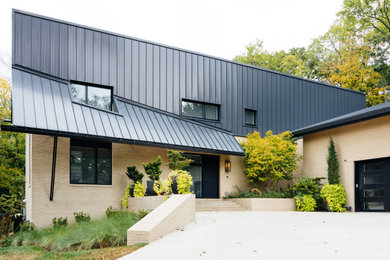This is an example of a large midcentury two-storey beige house exterior in Nashville with a metal roof.
