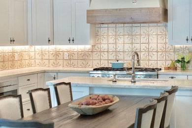 Example of a large tuscan u-shaped medium tone wood floor open concept kitchen design in Phoenix with an undermount sink, recessed-panel cabinets, white cabinets, quartzite countertops, ceramic backsplash, stainless steel appliances and an island