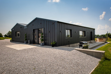 Photo of a medium sized and black modern bungalow front detached house in Other with metal cladding, a pitched roof, a metal roof and a black roof.