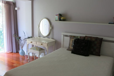Eclectic guest bedroom in Sydney with purple walls and medium hardwood floors.