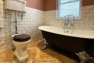 Inspiration for a medium sized bathroom in London with a freestanding bath, a two-piece toilet and brown floors.